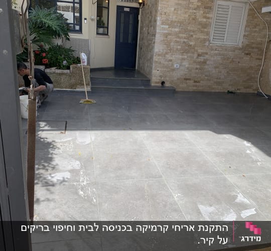 אדם עובד על רצפת אריחים עם דלי ומטאטא